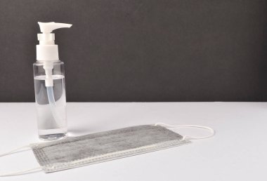 Beyaz arka planda yüz maskesi olan el dezenfektanı. Seçici odak.