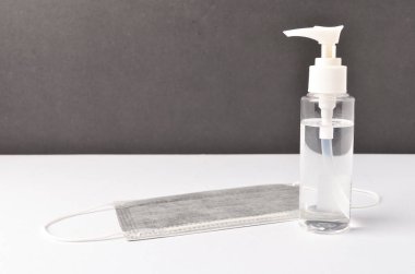 Beyaz arka planda yüz maskesi olan el dezenfektanı. Seçici odak.