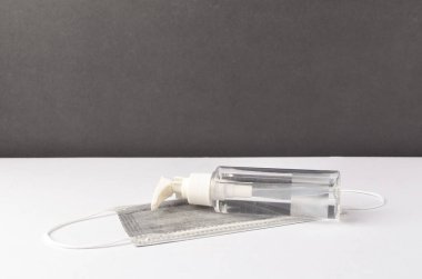 Beyaz arka planda yüz maskesi olan el dezenfektanı. Seçici odak.