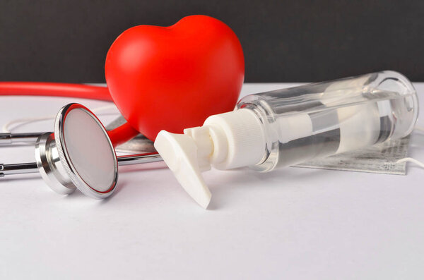 Hand sanitizer with face mask on white background. Selective focus.