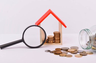 Konut kredisi almak için para biriktirmek hayat amacı için para biriktirmek. Beyaz arka planda bozuk paraları olan tahta bir oyuncak ev. Seçici odak.