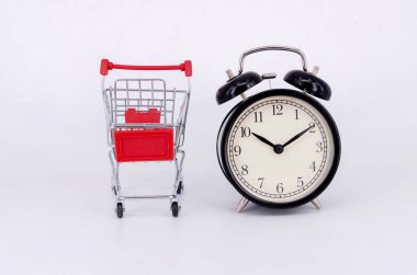 Alışveriş arabası ve beyaz arka planda klasik çalar saat. Satış zamanı alışveriş merkezi market tüketicisi konsepti satın al. Seçici odak.