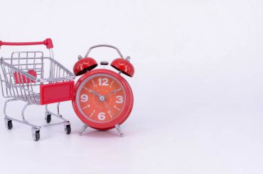 Alışveriş arabası ve beyaz arka planda klasik çalar saat. Satış zamanı alışveriş merkezi market tüketicisi konsepti satın al. Seçici odak.