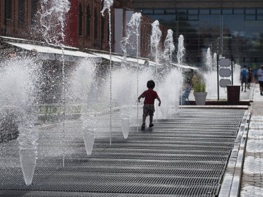 Küçük çocuk çok sıcak yaz gününde çeşme altında oynuyor