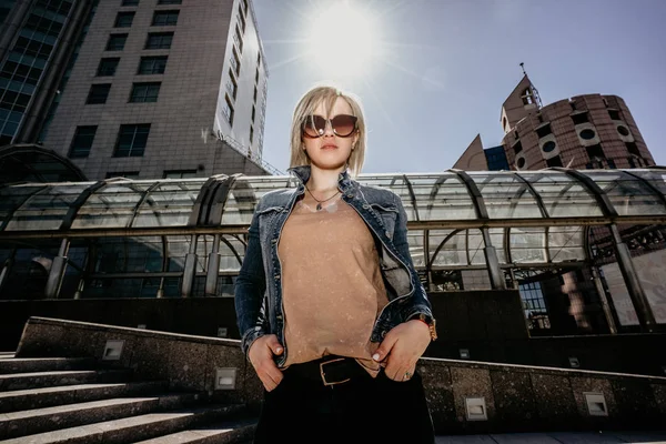 Jovem mulher moderna em óculos de sol no fundo de arranha-céus. Vida na cidade moderna — Fotografia de Stock