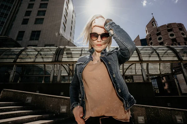 Lonely Modern woman straightens loose white hair. Life in a big city