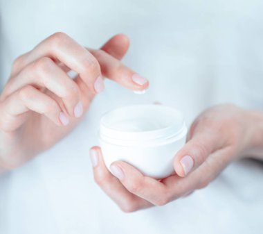 Kadın dövmeli eller bir kavanoz krema tutuyor. Beyaz krem bir damla ile Parmak