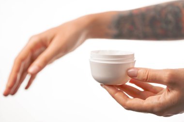 Krem bir kavanoz tutan kadın dövmeli eller