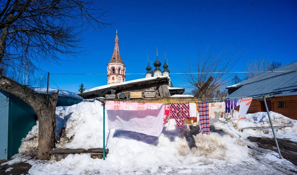 Kilisenin kubbelerinin arka planına karşı halat üzerinde temiz çarşafların asılı olduğu bir köy avlusu. Rusya'ya seyahat edin. Suzdal Stok Fotoğraf