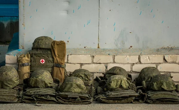 Vojenské přilby leží v řadě na asfaltu vedle soupravy první pomoci. Ambulance Royalty Free Stock Fotografie