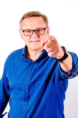 Gözlüklü ve mavi gömlekli orta yaşlı adamları işaret ediyor.