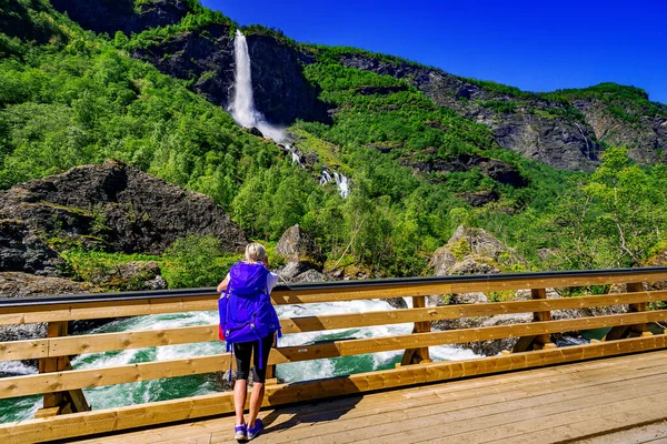 Hiker looking on landscape with waterfall in Norway
