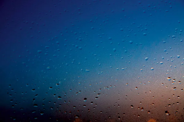 Raindrops on the glass in blue and orange.