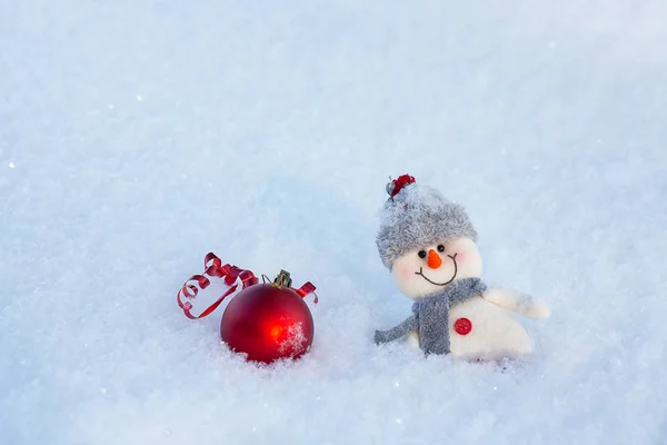 幸せな面白い雪だるまと雪の上の赤いクリスマス ボール 雪だるまには 毛皮の帽子とスカーフを着ています 寒い休日の概念 — ストック写真