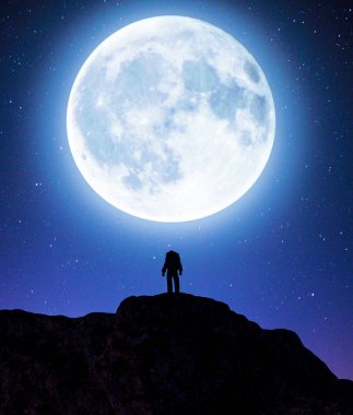 Büyük ay ile bir dağ zirvesinin tepesinde Astronot