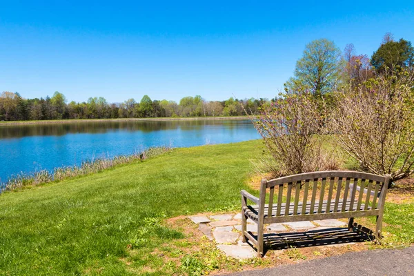 在阳光明媚的春天 Bautiful 湖附近有森林倒影的长凳 乡村春天风景 — 图库照片