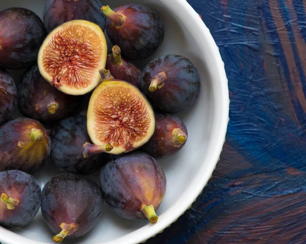 Figs fruits in a bowl on dark background, top view.