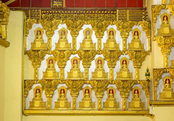 Socha Buddhy s mnoha malými Buddhy na zdi v buddhistickém temu — Stock fotografie