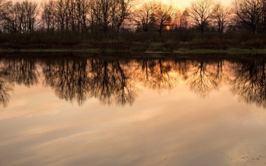 Nehrin üzerinde gün batımı, pembe gökyüzünün yansıması.