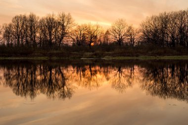 Nehrin üzerinde gün batımı, pembe gökyüzünün yansıması.