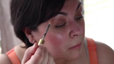 Kadın kendini, bir aynadaki göründüğü Vakfı makyaj koymak için bir değnek kullanır.