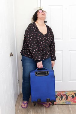 A woman arrives home from a trip and collapses against her door with suitcase  clipart