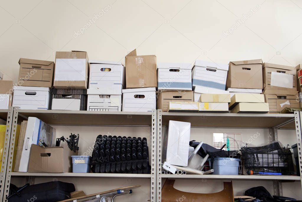  A stack of office supplies piled high in a storage room includes bankers boxes 