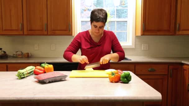 厨房岛上的妇女被蔬菜包围 正在用一把锋利的刀切洋葱 — 图库视频影像