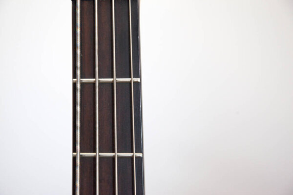 The neck of a bass guitar against white copy space