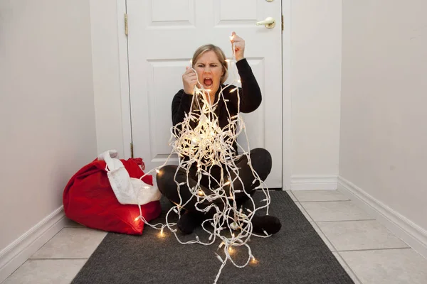 一个沮丧的女人无法解开圣诞灯 所以她愤怒地尖叫 — 图库照片
