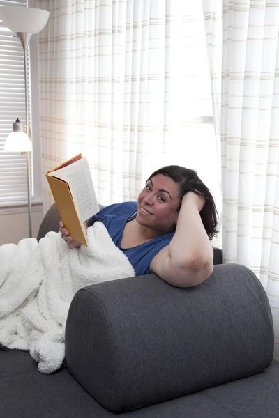 Grinning at home with a book — Stock Photo, Image