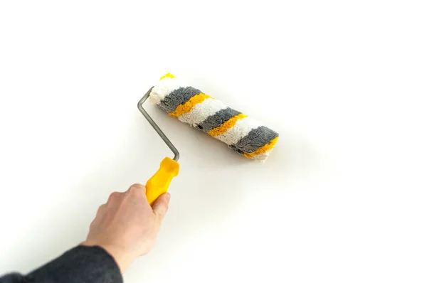 Bir duvar boya silindiri ile boyama ressam kolu kapatın. El fırça rulo üzerinde beyaz izole.