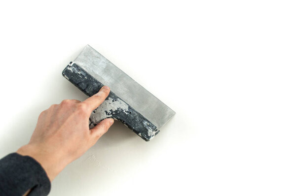 Man plastering the walls with finishing putty in the room with putty knife or spatula. Repair work, decoration building concept, construction.