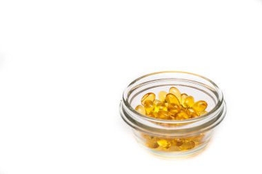 Beyaz arka plan üzerinde D vitamini takviyesi izole bir cam levha içinde balık yağı kapsülleri. Tabak balık yağı ve balık yağı. Sağlık ve uzun ömür kavramı.