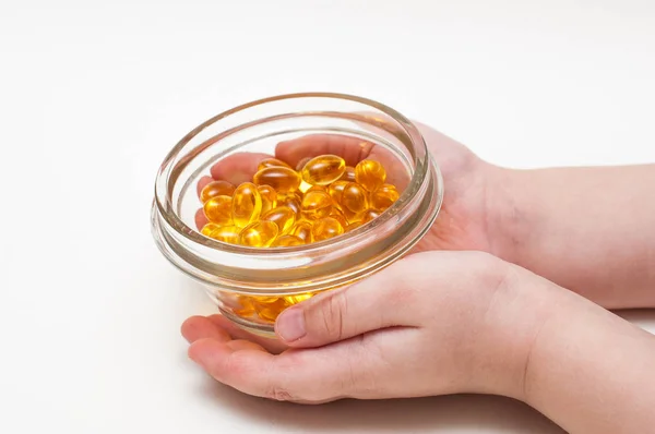 Çocuk ellerini omega 3 kapsülleri beyaz arka plan üzerinde izole tutmak. Sağlık ve uzun ömür kavramı.