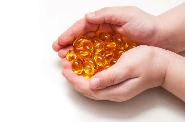 Çocuk ellerini omega 3 kapsülleri beyaz arka plan üzerinde izole tutmak. Sağlık ve uzun ömür kavramı.