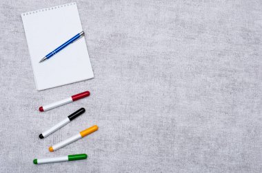 Bir not defterinin işaretleyici, renkli işaretler ve gri arka plan üzerinde şık mavi kalem le görüntülenme. Yazınız veya eklemeniz için alan içerir. İş ve yaratıcılık kavramı.