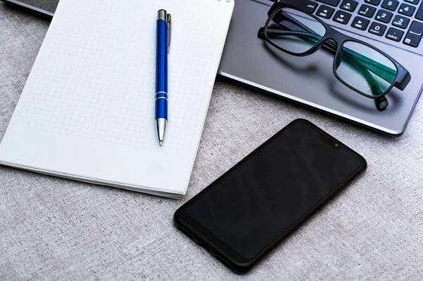 İş ve finans kavramı ofis çalışması, iş günü ofis masası. Masaüzerinde dizüstü not defteri, gözlük ve akıllı telefon içeren masa işyeri.