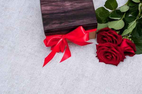 Tasarım veya montaj için taze kırmızı gül ve boş alan ile birlikte kırmızı bir kurdele ile güzel bir hediye kutusu. Tatil ve hediyeler kavramı.