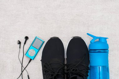 Düz yatıyordu spor ayakkabı, su şişesi, dambıl ve kulaklık gri beton arka plan üzerinde. Kavram sağlıklı yaşam tarzı, spor ve diyet.