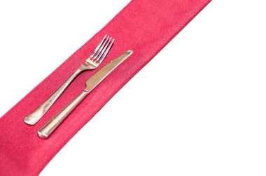 Masanın üzerinde ipek bir peçete üzerinde metal çatal ve bıçak.