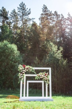 Açık havada çiçeklerle süslenmiş düğün kemeri. Güzel bir düğün ayarlandı. Bahçedeki yeşil çimenlerde düğün töreni. Şenlikli dekor, çiçek düzenleme parçası.