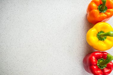 Beyaz bir mutfak masasında renkli tatlı biber. Kopyalama alanı ile üstte görünüm.