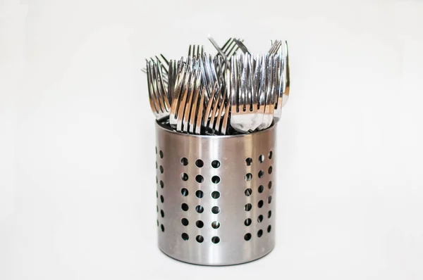 Silvery forks stand in a metal stand on a white background. And one fork is higher than the rest. The concept of social behavior and voting.
