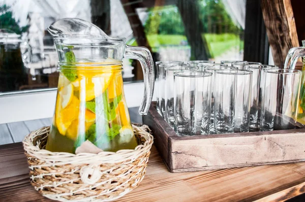 A jug of homemade refreshing icy citrus lemonade on the terrace on a hot summer day. Concept of detox diet.