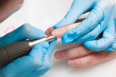 Kadın güzellik salonunda elektrikli tırnak dosyası matkap kullanın. Mükemmel çivi manikür işlemi veya yakın çekimde çalışma.