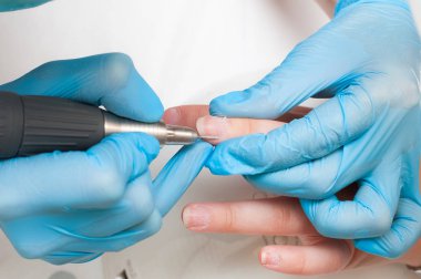 Kadın güzellik salonunda elektrikli tırnak dosyası matkap kullanın. Mükemmel çivi manikür işlemi veya yakın çekimde çalışma.