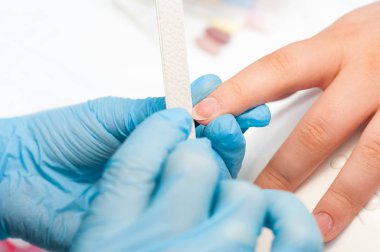 Closeup çekim tarafından bir güzellik tırnak törpüsü ile manikür alma bir tırnak salonu içinde bir kadın. Kadın Başlarken tırnak manikür. Şevval Özçelik Güzellik dosya bir müşteriye çivi.