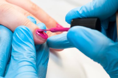 Manikür tırnak boya pembe renk. Tırnak bakımı. Spa salonunda manikür yaptıran güzel kadın ellerinin yakın çekimi. Profesyonel manikür ile kadın manikürcü temizlik kütikül. Kozmetik prosedür.