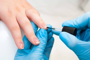 Bakımı ve manikür çivi. Closeup şeffaf oje güzellik salonu sağlıklı doğal kadının çivi uygulayarak güzel eller. Manikürcü el boyama müşterinin çivi.